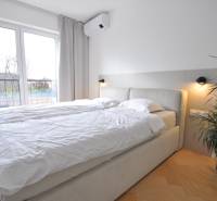 Schlafzimmer in einem Einfamilienhaus mit Bett, Pflanze und Boden in Holzoptik.