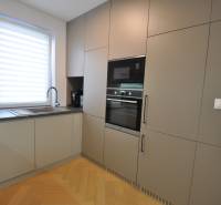 Eine Küche in einem Einfamilienhaus mit einem Boden in Holzoptik und eingebauten Geräten.