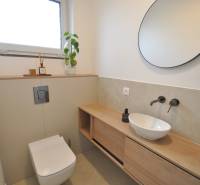 Badezimmer in einem Einfamilienhaus mit rundem Spiegel, Waschbecken und Boden mit Holzdekor.