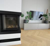 Wohnzimmer in einem Einfamilienhaus mit Kamin, Fernseher und Boden in Holzoptik.