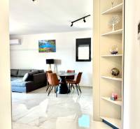 Innenraum einer Einzimmerwohnung mit weißem Boden, grauem Sofa und Esstisch.