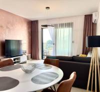 Wohnzimmer in einer Einzimmerwohnung mit Fernseher, Balkon und elegantem Tisch.