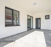 Ein Einfamilienhaus mit Terrasse, großen Fenstern und einem grauen Boden mit Fliesen.