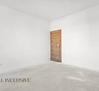 Ein leerer Raum in einem Einfamilienhaus mit weißen Wänden und einer Tür mit Holzdekor.