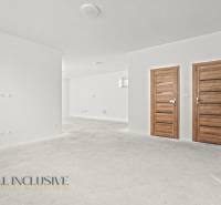 Weiße Wände und Holztüren im Inneren eines Einfamilienhauses mit einem Boden ohne Dekor.