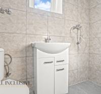 Ein Badezimmer in einem Einfamilienhaus mit Waschbecken, Dusche und Toilette in hellen Fliesen.