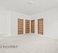 Ein geräumiger Raum in einem Einfamilienhaus mit weißen Wänden und Türen in Holzoptik.