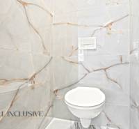 Ein Badezimmer in einem Einfamilienhaus mit luxuriösen Fliesen und einer eingebauten Toilette.