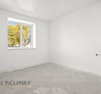 Ein leerer Raum in einem Einfamilienhaus mit weißen Wänden und einem Fenster mit Blick auf Bäume.