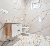 Badezimmer in einem Einfamilienhaus mit Keramikfliesen und Möbeln in Holzoptik.