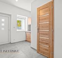 Weißer Flur eines Einfamilienhauses mit Holztüren und Keramikboden.