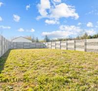 Der Garten eines Einfamilienhauses in Orechová Potôň mit einer Betonmauer und einer Rasenfläche.