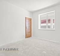 Ein Einfamilienhaus mit einer weißen Wand und einer Holztür, ein Fenster mit Blick auf das Dach.