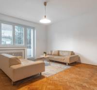 Wohnzimmer in einer 3-Zimmer-Wohnung mit beigen Sofas und einem Boden in Holzoptik.