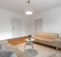 Wohnzimmer in einer 3-Zimmer-Wohnung mit hellen Sofas und einem Boden in Holzoptik.