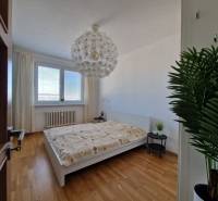 Schlafzimmer in einer 3-Zimmer-Wohnung mit Bett, weißen Wänden und Boden in Holzoptik.