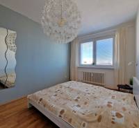 Schlafzimmer in einer 3-Zimmer-Wohnung mit bequemem Bett, Spiegel und Holzboden.