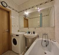 Badezimmer in einer 3-Zimmer-Wohnung mit Badewanne, Waschmaschine und großem Spiegel.