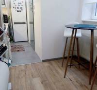 Küche in einer Einzimmerwohnung mit Holzboden, hoher Tisch und Stühle.