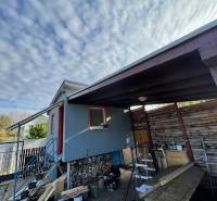 Ein Haus in Komárno in der Neusiedlung mit einer Treppe und einem hölzernen Unterstand unter den Wolken.