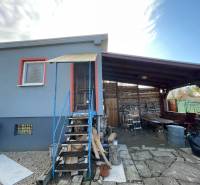 Ein Ferienhaus in Komárno in der Neuen Siedlung mit überdachter Terrasse und Holztreppe.