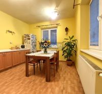 Wohnzimmer in einem Einfamilienhaus mit großer Eckcouch und Boden in Holzoptik.