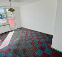 Ein Zimmer in einer Einzimmerwohnung mit farbigem Boden und großen Fenstern, Blick auf die Natur.