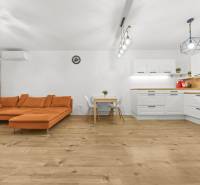 Wohnzimmer in einer 2-Zimmer-Wohnung mit einem orangefarbenen Sofa und einem Holzboden.