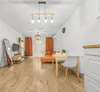 Wohnzimmer in einer 2-Zimmer-Wohnung mit Holzboden und orangenen Möbeln.