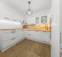 Eine Küche mit weißen Schränken, Holzarbeitsplatten und einem Boden in Holzoptik in einer Zweizimmerwohnung.