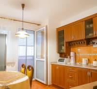 Küche in einer 2-Zimmer-Wohnung mit Holzschränken, Esstisch und Zugang zum Balkon.