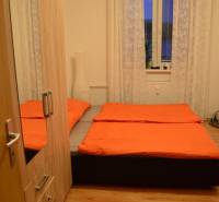 Schlafzimmer in einer 2-Zimmer-Wohnung mit orangefarbener Bettwäsche und Holzboden.