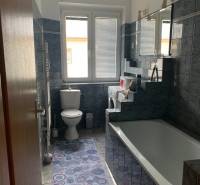 Badezimmer in einer 2-Zimmer-Wohnung mit blauen Fliesen, Badewanne und Waschbecken.