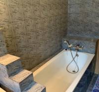 Badezimmer in einer 2-Zimmer-Wohnung mit Badewanne und Marmorfliesen.