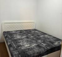 Schlafzimmer in einer 2-Zimmer-Wohnung mit Bett, hellen Wänden und Boden in Holzoptik.