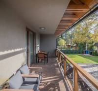 Balkon einer 2-Zimmer-Wohnung in Tatranská Lomnica mit Holzboden und Gartenmöbeln.