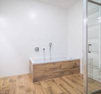 Badezimmer in einer 2-Zimmer-Wohnung mit Badewanne und Boden in Holzoptik.