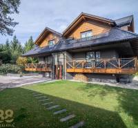Ein zweistöckiges Haus mit Holzelementen und einem grünen Rasen in Tatranská Lomnica.