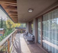 Der Balkon einer 2-Zimmer-Wohnung in Tatranská Lomnica mit einem Boden in Holzoptik und Blick ins Grüne.