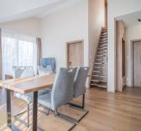 Wohnzimmer mit Esstisch und Treppe in einer 2-Zimmer-Wohnung, Boden mit Holzdekor.