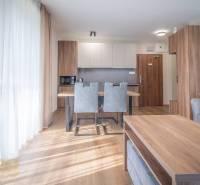 Innenraum einer 2-Zimmer-Wohnung mit Küchenzeile, grauen Stühlen und einem Boden in Holzoptik.