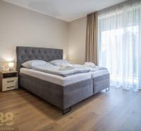 Schlafzimmer in einer 2-Zimmer-Wohnung mit einem großen Bett und einem Boden in Holzoptik.