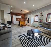 Wohnzimmer mit Küche in einem Einfamilienhaus, Boden mit Holzdekor, Ziegelwand.