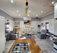 Wohnzimmer in einem Einfamilienhaus mit Sofas, Küche und Holzboden.