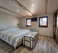 Ein Schlafzimmer in einem Einfamilienhaus mit einem Bett, einem dekorativen Koffer und einem Boden mit Holzdekor.