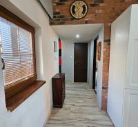 Ein Flur mit einer Ziegelwand und einer Uhr, ein Boden mit Holzdekor, Möbel aus Holz.