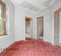 Ein Einfamilienhaus mit roten Fliesen, verputzten Wänden und drei offenen Durchgängen.