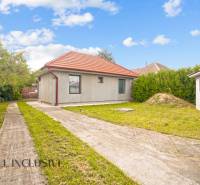 Ein Einfamilienhaus in Bátorove Kosihy, mit Rasen, Betonweg und rotem Dach.