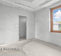 Innenraum eines Einfamilienhauses mit unvollendeten Wänden und großem Fenster.