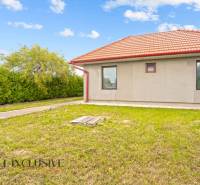 Ein Einfamilienhaus in Bátorove Kosihy mit einem roten Dach, umgeben von grünem Rasen und Sträuchern.